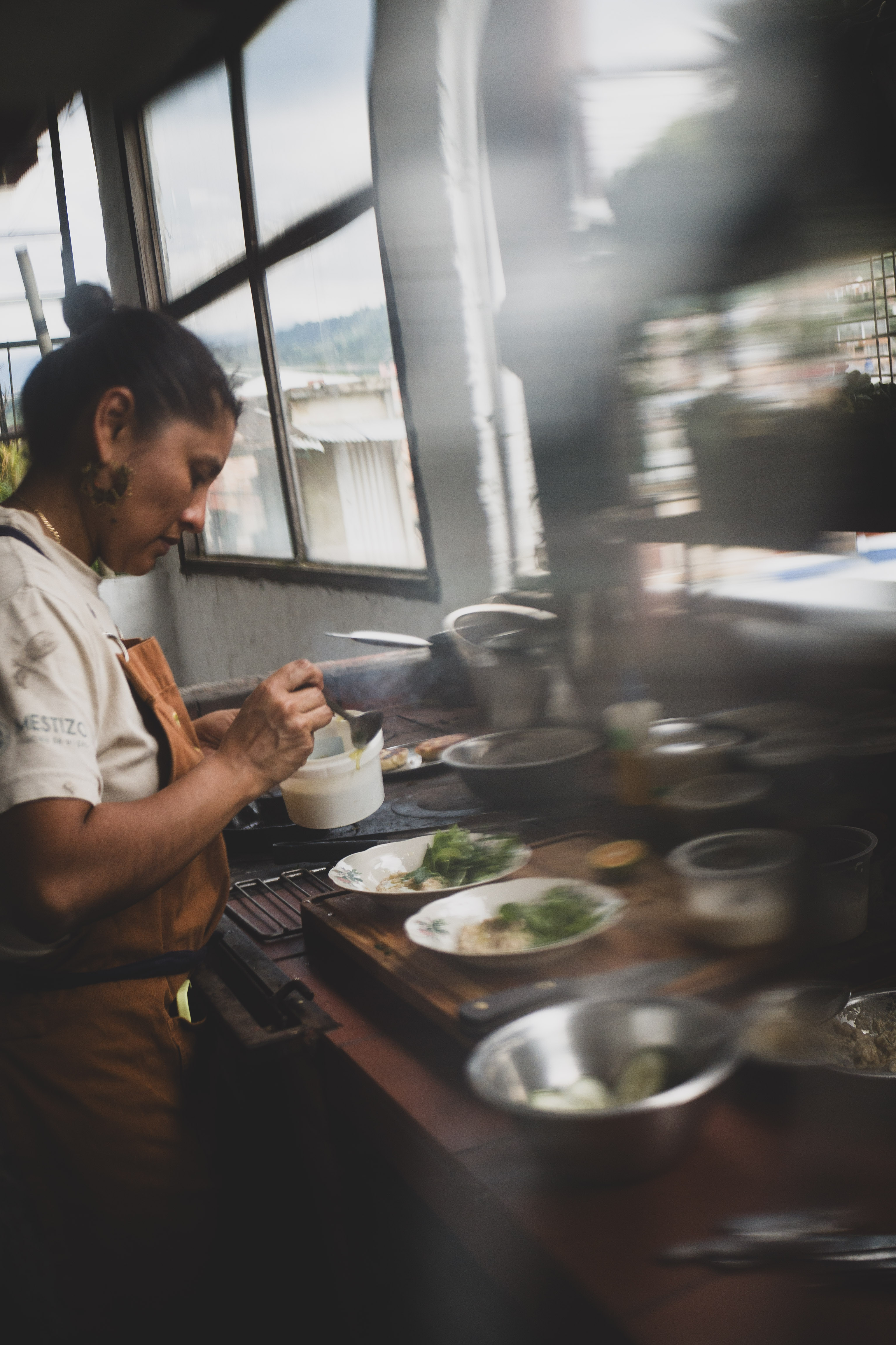 Una cocinera sirve una salsa sobre platos dispuestos en una mesa de trabajo.