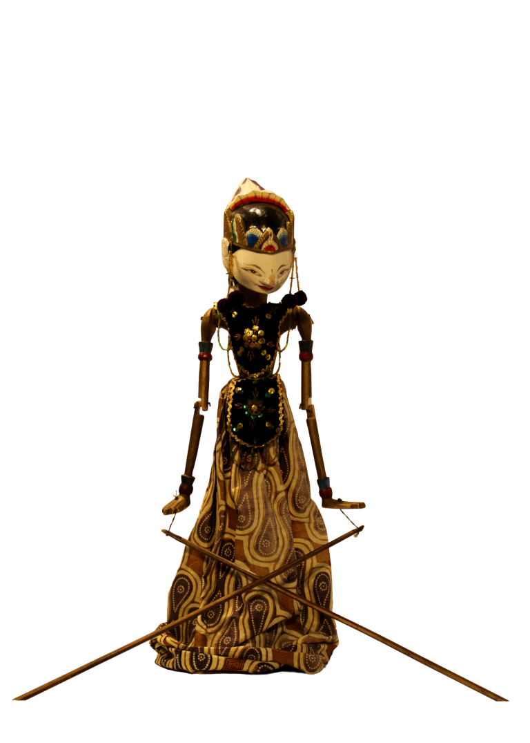 Marioneta wayang golek con blusa negra bordada y falda de batik en tonos tierra.