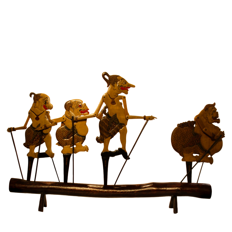 Cuatro marionetas planas de wayang klitik clavadas sobre un tronco de madera.