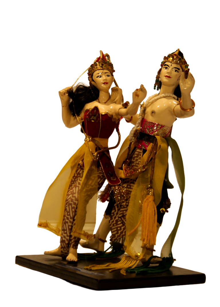 Arjuna y Srikandi: dos figuras con tocados dorados y paños de gasa amarilla sobre base negra rotulada.
