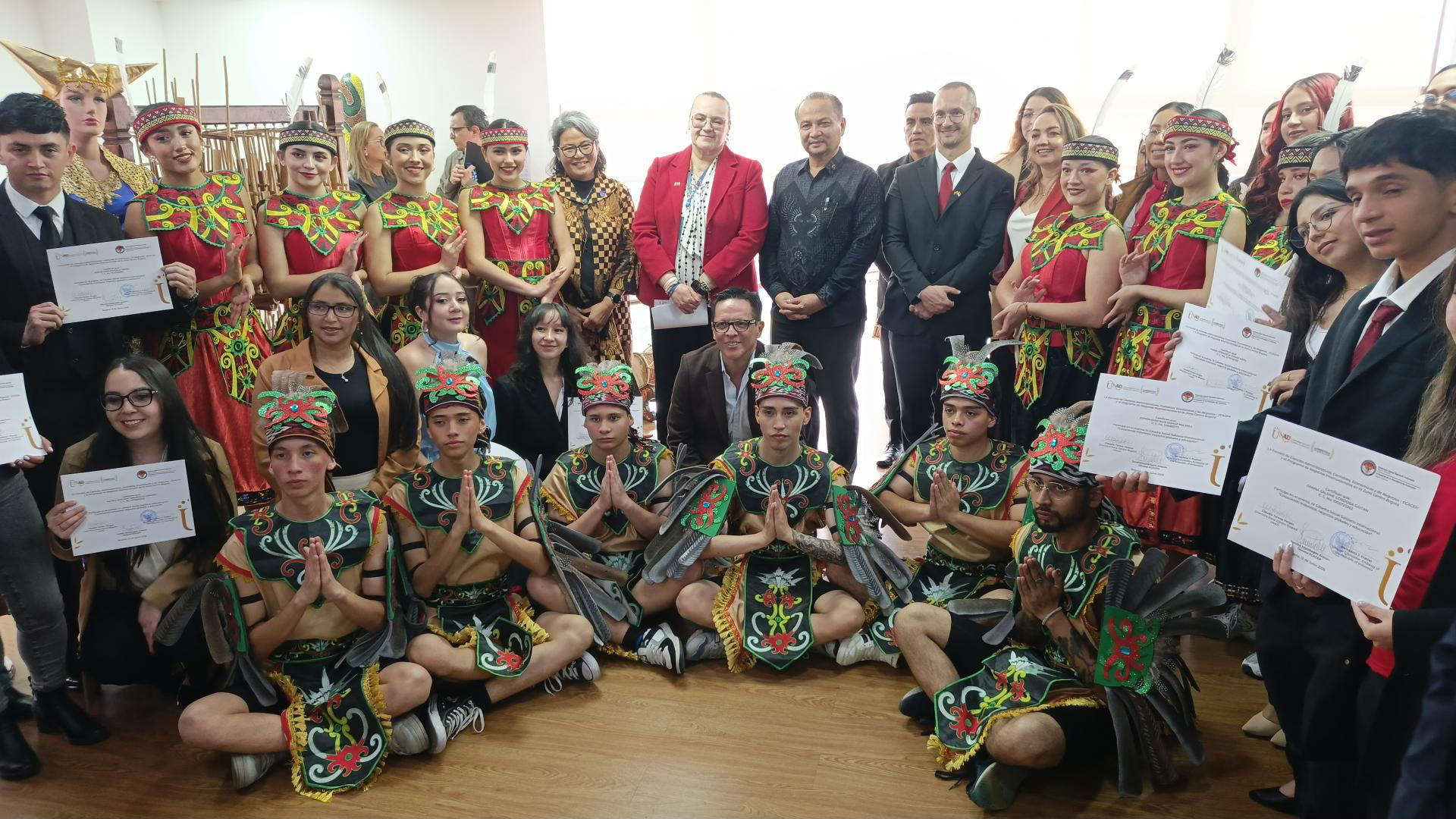 Fotografía de grupo al cierre del acto: participantes, bailarines y delegación posando con certificados.